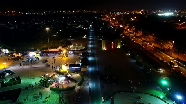 Stunning aerial night shot of illuminated Kish Island with modern architecture and vibrant seafront activity.