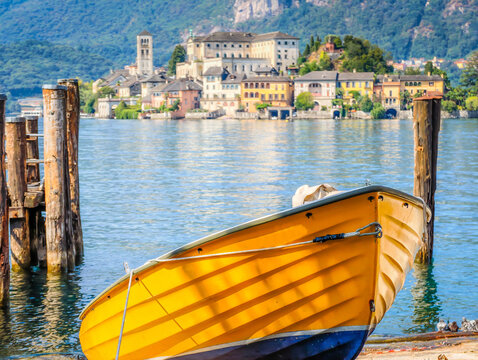 Traditional Italian atmosphere on Lake Orta, with a boat resting along the lakeshore and picturesque San Giulio Island in the background, Piedmont, Italy
