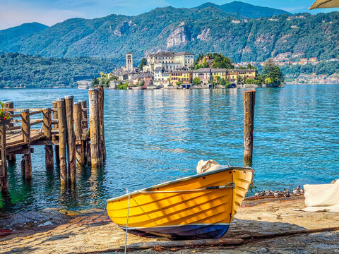 Traditional Italian atmosphere on Lake Orta, with a boat resting along the lakeshore and picturesque San Giulio Island in the background, Piedmont, Italy