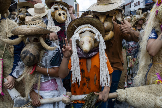 View of participants wearing traditional gourd masks and straw hats during a cultural festival in Michoacan, Mexico.