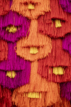 View of vibrant, hand-woven textile tassels from an Ahuiran rebozo, featuring bright orange, red, and purple threads with yellow accents in Ahuiran, Michoacan, Mexico.