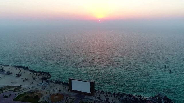 Peaceful aerial view of Kish Island sea at sunset with ship silhouette on horizon.