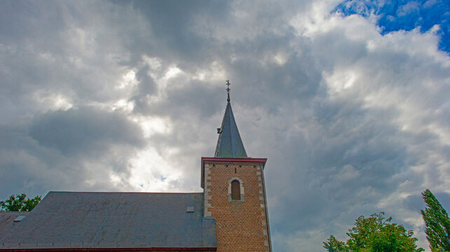 Trees and an old church in sunlight and shadow in green woodland in summer, Voeren, Limburg, Belgium, August, 2026