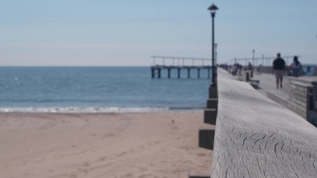 Coney Island beach, wooden pier promenade in Brooklyn, New York, United States. Boardwalk near retro luna park. Ocean coast sandy beach. Defocused people on waterfront summer holiday in NYC, USA.