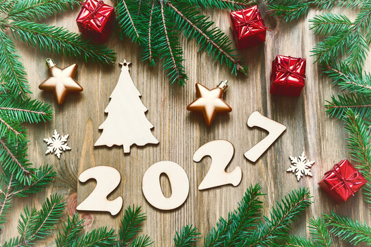 New Year background for 2027 year - composition made of 2027 wooden figures, Christmas toys and decorations, fir tree branches. Vintage tones, flat lay, top view