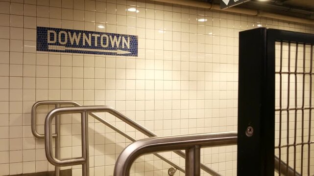 New York City Manhattan Midtown underground subway, Downtown metro direction, United States railway. Public metropolitan transport in USA, american railroad navigation. Sign on wall, tiles and arrow.