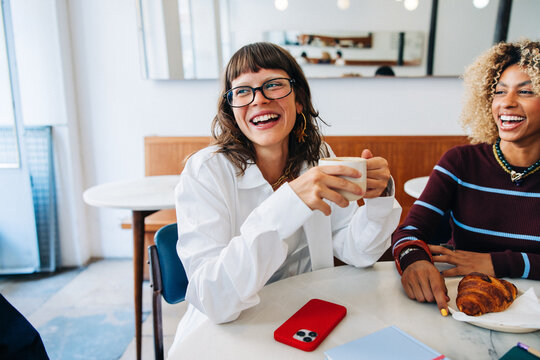 Friends laughing over coffee in cozy cafe