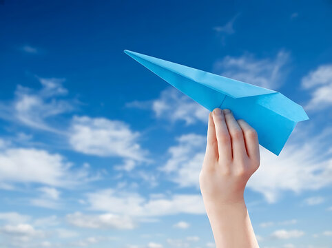 Hand holding a blue paper airplane against a bright sunny sky for travel and innovation