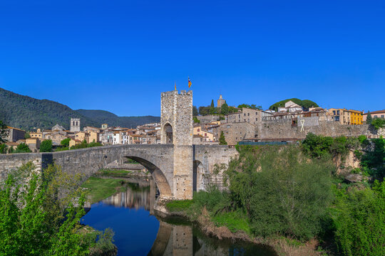 View of Romanesque bridge and town with Fluvia river, Besalu, Spain. Panoramic scenery, sunny daytime style