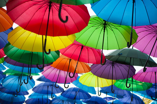 Rows of rainbow-colored umbrellas create a bright outdoor canopy, festive street decoration, vibrant creative background.