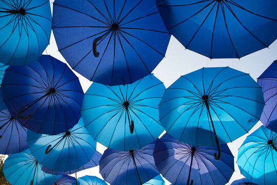 Blue and cyan umbrellas overlap against the sky, colorful outdoor canopy, creative decorative display, festive summer background.