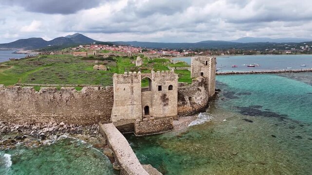 Drone aerial shot moving around Methoni Venetian castle stone walls and stone bridge, revealing the octagonal Bourtzi tower surrounded by turquoise Mediterranean sea in Messenia, Greece