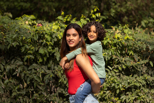 Little boy riding on his mother's back in the park
