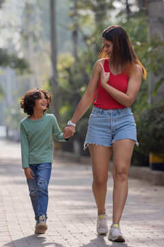 Mother showing victory symbol to her son while walking together in the park