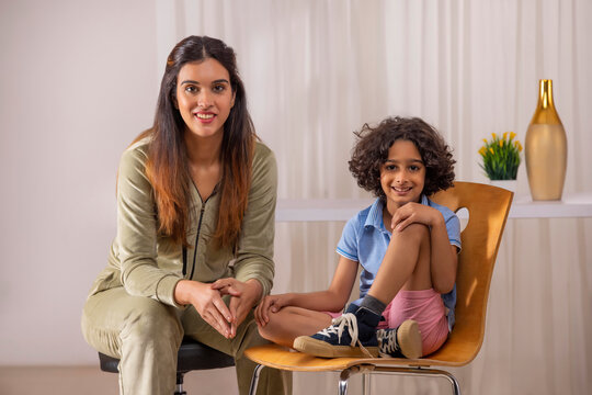 Mother and son looking at camera together while sitting in living room 