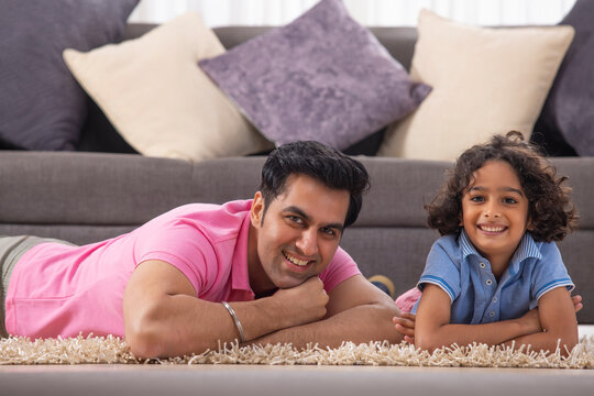 Father and Son lying down on carpet and looking at camera with smile