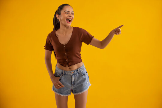 Young woman gesturing while standing against yellow background