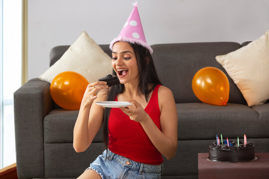 Young woman with party hat eating birthday cake