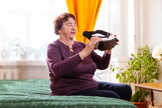 Elderly Caucasian woman experiences immersive virtual reality while spending quiet time at home. Comfortable retirement and modern digital entertainment concept.