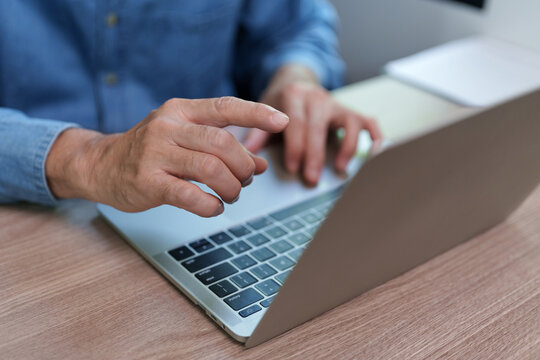 Businessman using a laptop and keyboard at a desk, representing remote business, productivity, technology, workflow and modern office tasks.