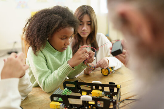 Diverse children assemble and program a robotics project in a STEM classroom, building engineering, coding, teamwork, and creative problem-solving skills.