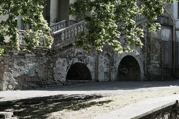 Naklejka premium Exterior of an abandoned building with arched brick foundations and old staircase