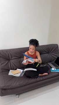 Young woman studying business documents on a sofa