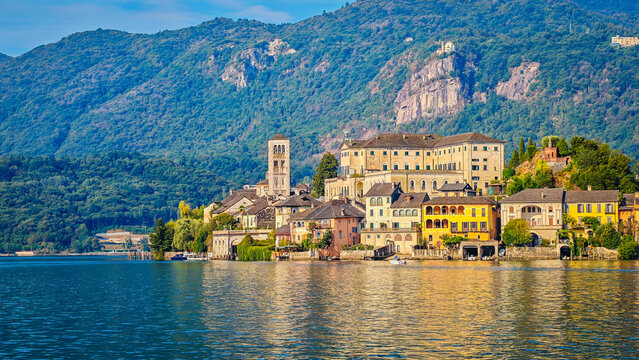 Panoramic view of San Giulio Island on Lake Orta during a golden hour and sunset, Piedmont, Italy, featuring the historic basilica and picturesque lakeside scenery surrounded by Alpine landscapes
