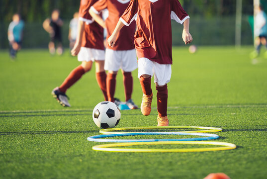 Junior Soccer Player Stepping Through Agility Hoops During Team Drill - Youth Football Footwork Training on Grass Field