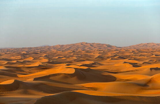 View of vast undulating sand dunes of the Liwa desert under a clear sky in Al Dhafra Region, Abu Dhabi, United Arab Emirates.
