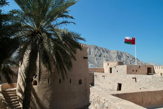Khasab Fort ramparts with Omani flag and palm tree, Musandam, Oman