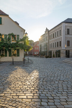 20 August 2026, Sunlight illuminates a cobblestone street and historic buildings in Iphofen, Bavaria, Germany.