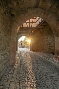 20 August 2026, Sunlight shines through the historic archway of the medieval town gate in Iphofen, Bavaria, Germany.