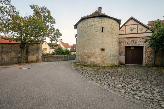 20 August 2026, Historic stone defense tower along a cobbled street in the wine town of Iphofen, Bavaria, Germany.