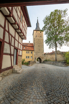20 August 2026, View of the historic town gate and half-timbered house along a cobblestone street in Iphofen, Bavaria, Germany.