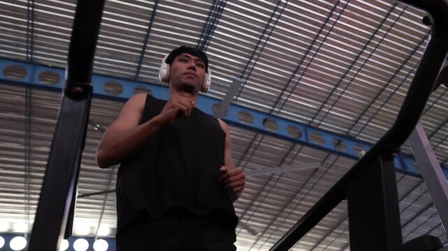 Athlete with headphones running on a treadmill at the gym.