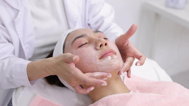 Esthetician performing a facial massage treatment in beauty spa.