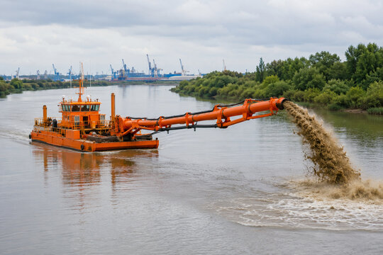 Orange dredger vessel with discharge pipe on calm river, industrial waterway and sediment concept