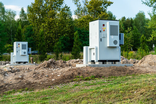 View of two industrial electrical cabinets installed on concrete pads in an outdoor construction site with trees in the background in Dabrowa Gornicza, Silesian Voivodeship, Poland.