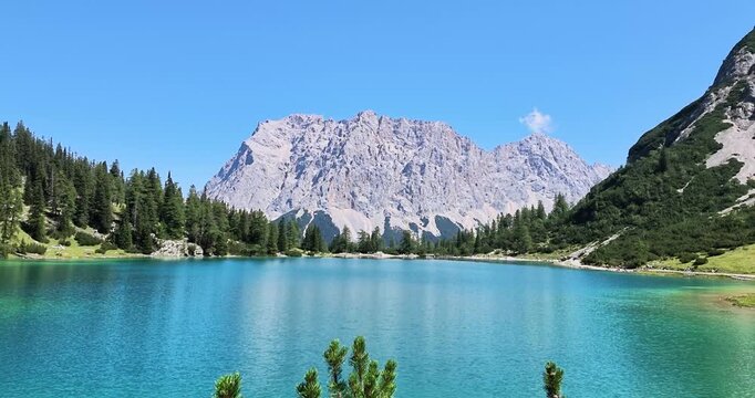 Real time scenic view over turquoise Seebensee framed by alpine forest and rugged mountain peaks in the Austrian Alps.
