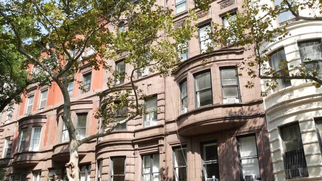 New York City townhouse buildings, brownstone row houses in Manhattan or Brooklyn, United States of America. Classic buildings on residential district street. Real estate property. Rowhouse townhome.