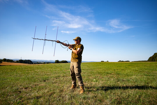 Amateur Radio Operator Using a Directional Yagi Antenna in an Open Field for Satellite Communication and Radio Direction Finding