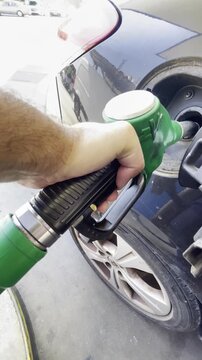 Gasolina llenar dep&oacute;sito derramar combustible con manguera de repostar autoservicio verter en gasolinera self service subida de precio litro petr&oacute;leo