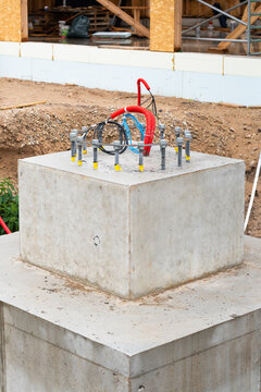 View of a concrete foundation block with protruding anchor bolts and electrical conduits at a construction site in Riga, Latvia.