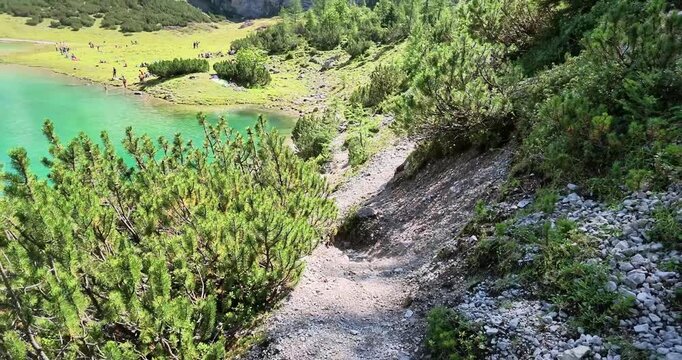Smooth real time panorama across turquoise Seebensee with alpine forest and rugged Zugspitze mountains in Tyrol Austria.