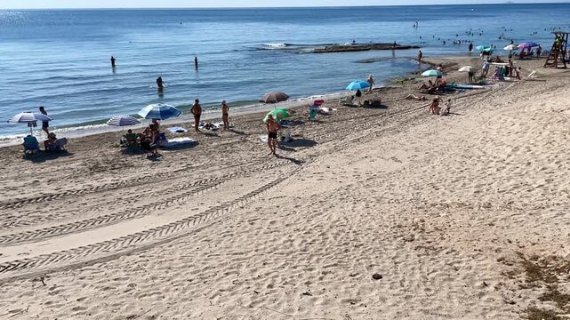 Playa y ba&ntilde;istas en vacaciones de verano al sol en mar con sombrilla, ba&ntilde;ador y arena