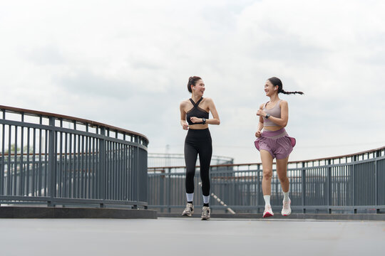 Asian women jogging together outdoors for outdoor cardio fitness and wellness