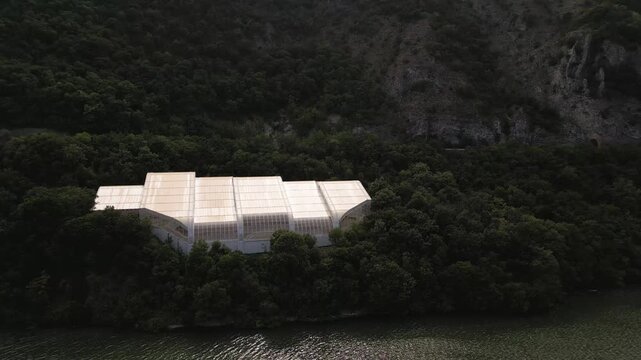 Aerial drone footage of the modern glass protective structure and visitor center at Lepenski Vir archaeological site in Iron Gate National Park, Serbia. 20.07.2026