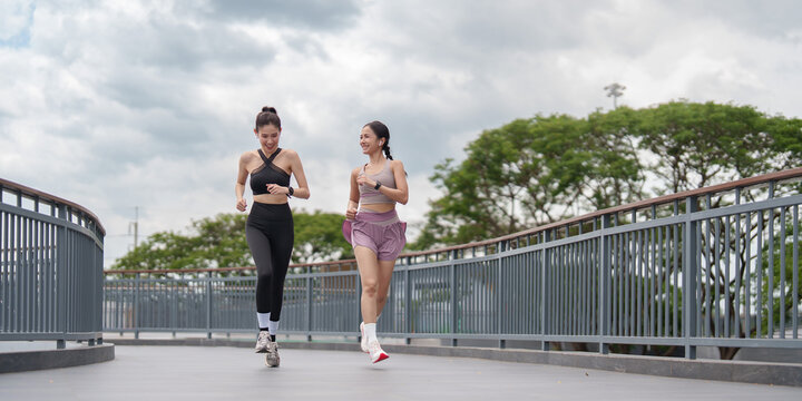 Two Asian women running together outdoors for marathon training and fitness