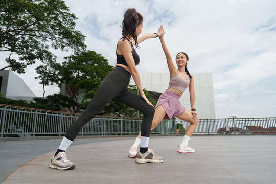 Asian women high five while stretching during outdoor workout